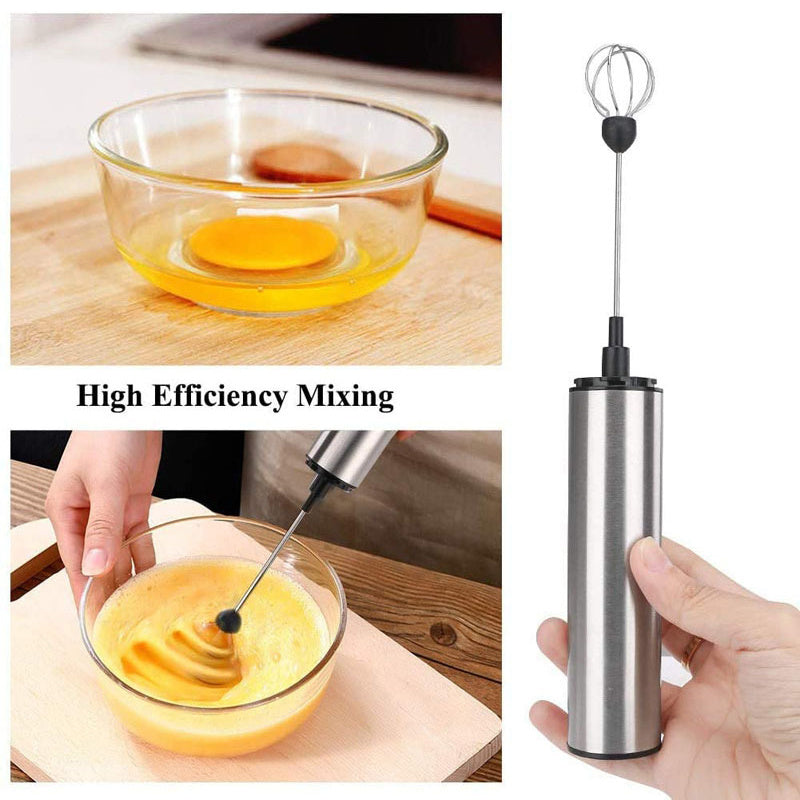 Handheld milk frother with eggs being whisked in a glass bowl on a wooden surface.