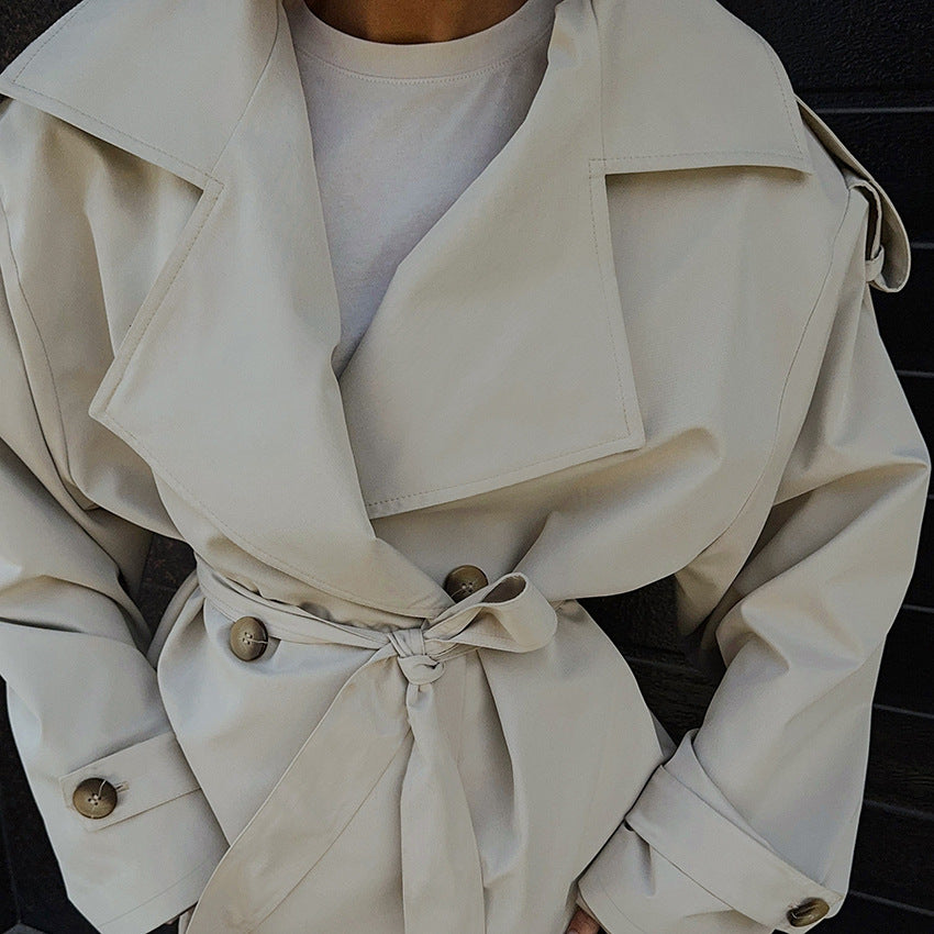 Close-up of a beige trench coat with a person wearing it.