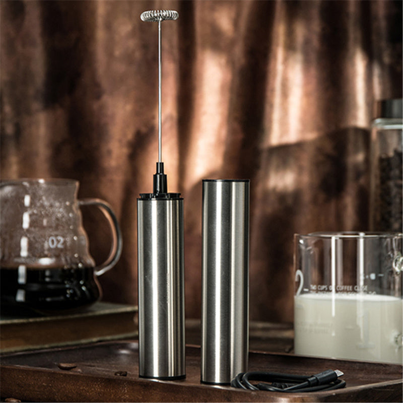 Metallic milk frother on a wooden surface with a blurred background