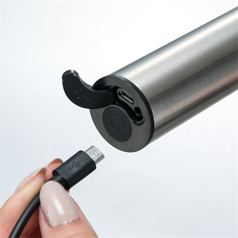 Hand holding a USB cable to a silver electronic device on a white background