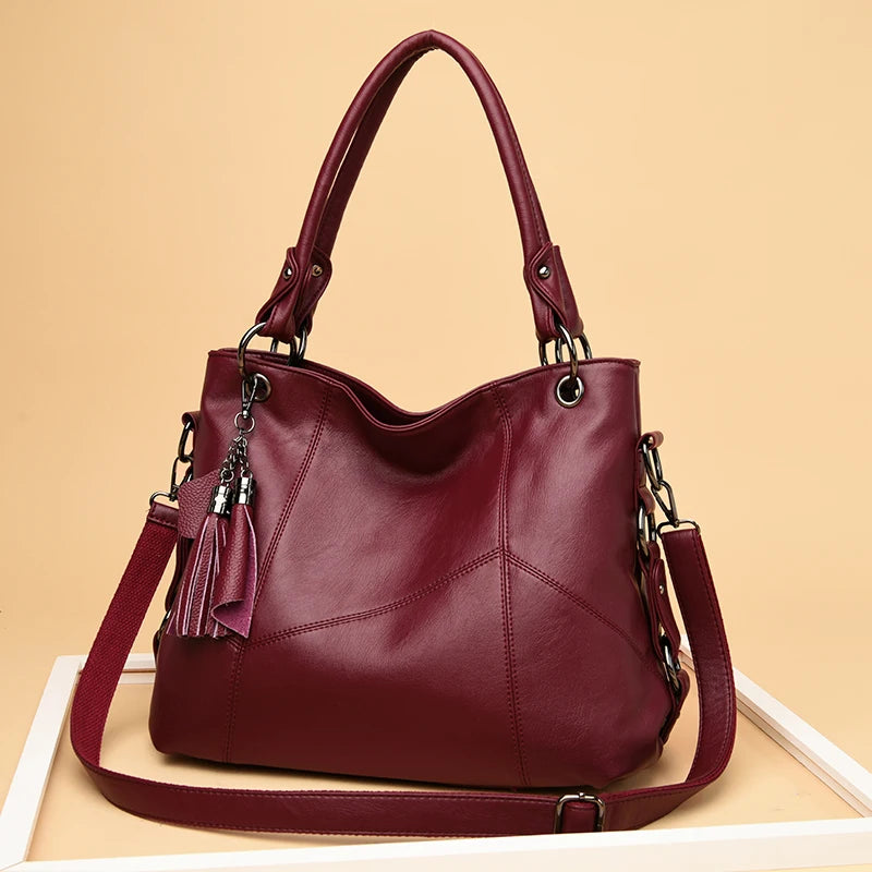 Maroon handbag with a strap and tassel on a beige background
