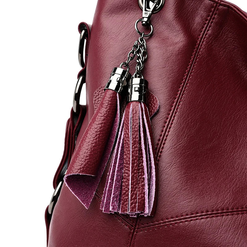 Maroon leather bag with tassel keychain on a white background