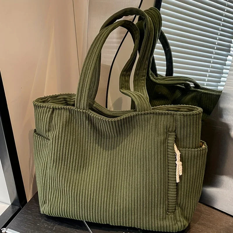 Green ribbed tote bag with a pocket on a surface