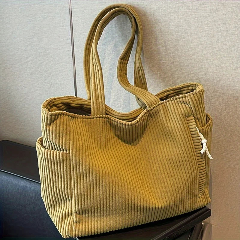 Yellow ribbed handbag on a surface with a neutral background