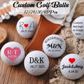 personalised golf balls UK - Six white golf balls with custom printed names, dates, and heart/logo designs arranged on a wooden surface with a brown strap and burlap. Text at the top reads 'Custom Golf Balls 12/24/36/48 Pcs' and one ball shows a pink heart logo with 'R+T'.