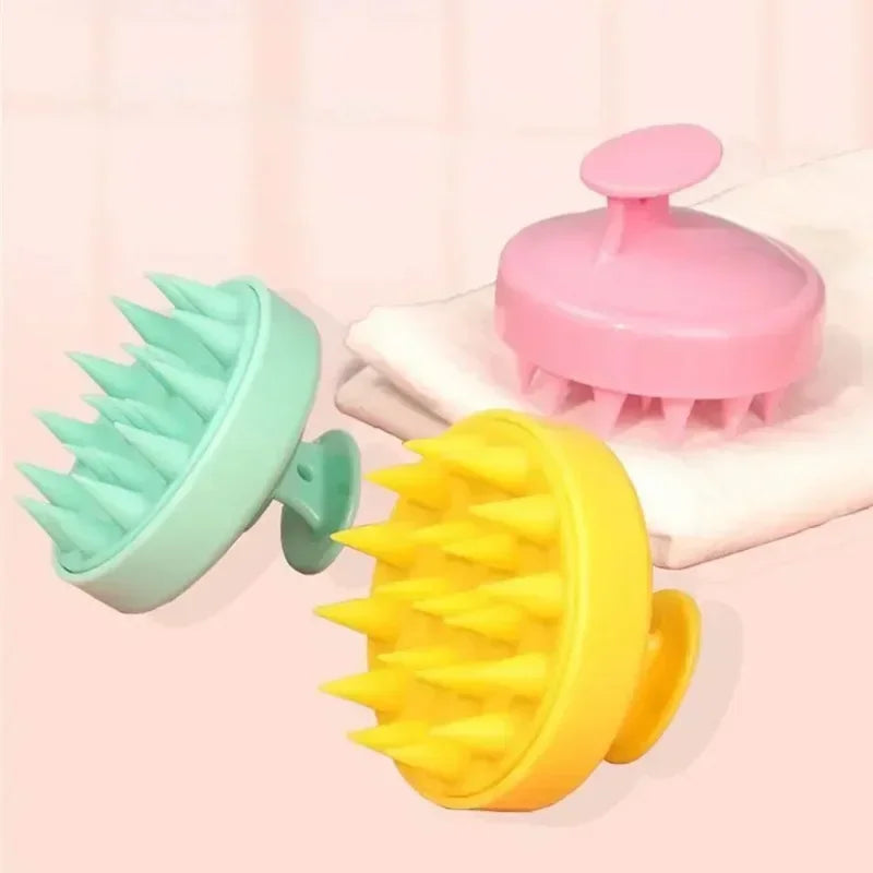 Three silicone scalp massagers in green, yellow, and pink on a light pink background