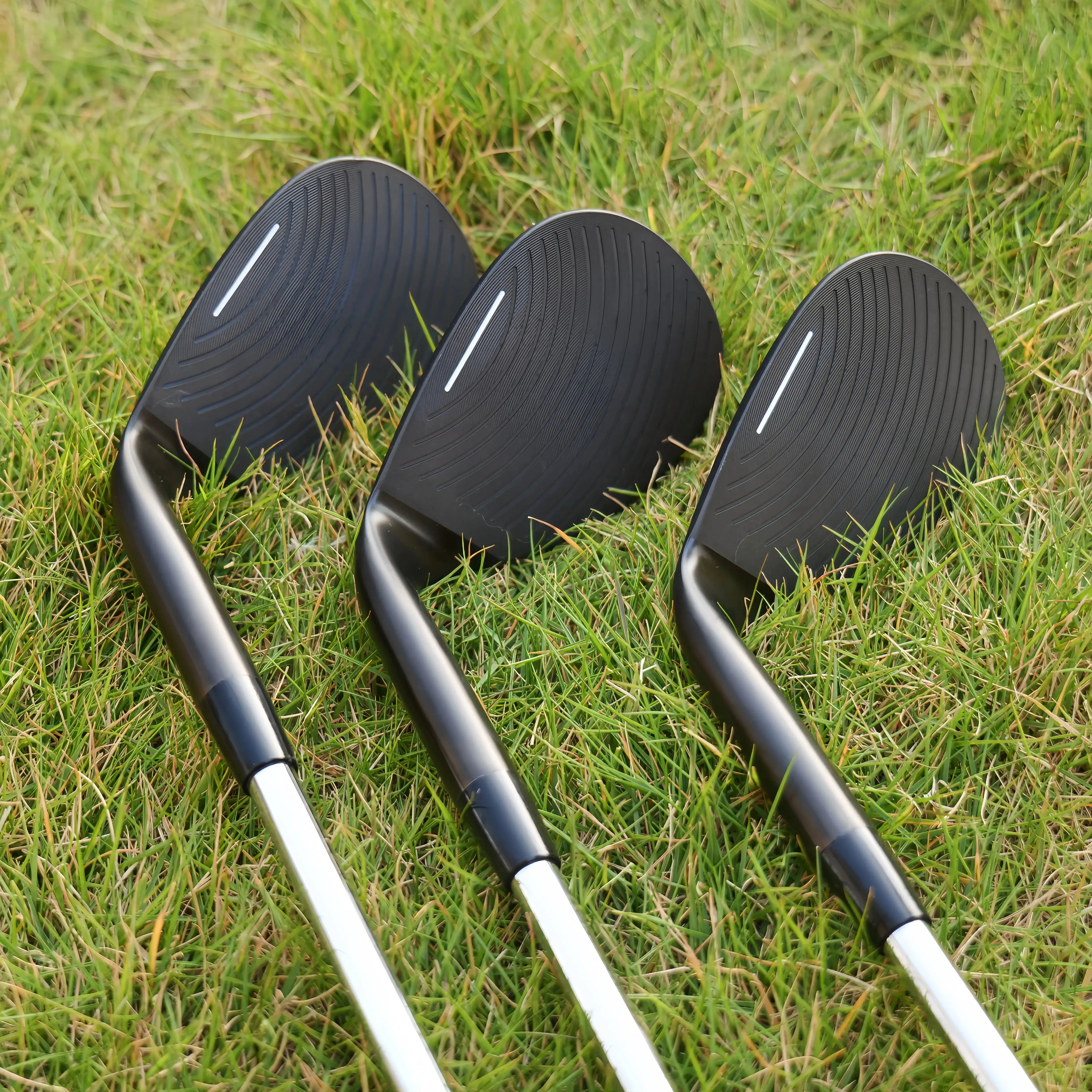 high loft golf wedge UK - Three golf club heads on a grassy background