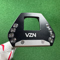 beginner golf putter UK - A VZN golf club head insert or clubface protector shown being held by a hand wearing a white and red golf glove, against a green turf background.