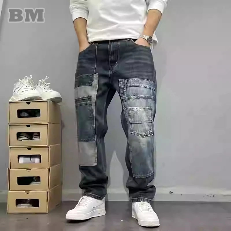 Person wearing patchwork jeans and white sneakers standing next to stacked cardboard boxes with shoes on a gray background.