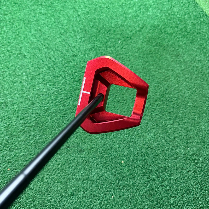 beginner golf putter UK - A close-up of a red metal golf putter head with a black shaft, resting on a green artificial turf background.