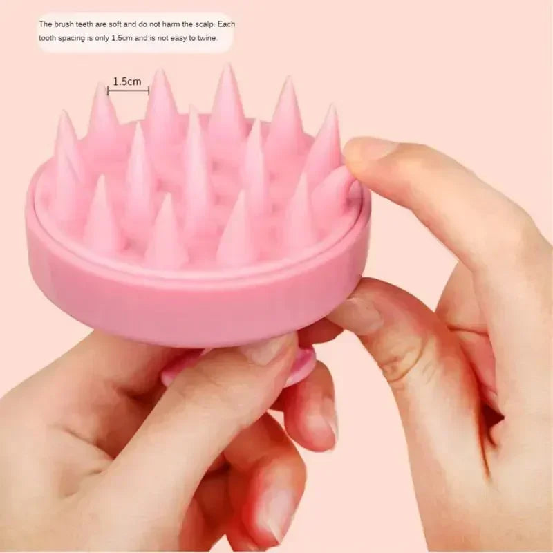 Pink scalp massage brush held by hands with a light pink background
