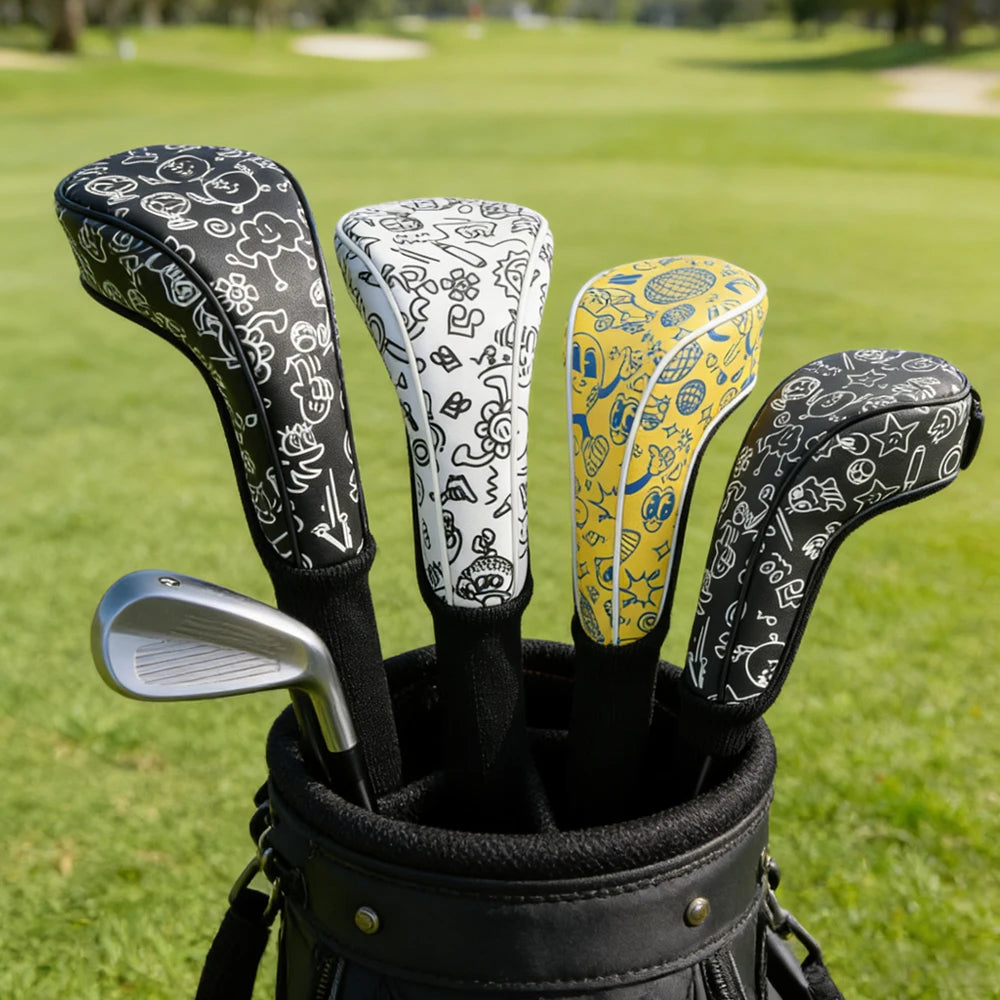 golf club head covers UK - A golf bag on a grassy golf course with four patterned golf club headcovers sticking out of the top. The headcovers are black, white, and yellow with hand-drawn doodle-style graphics, and a silver golf club is partially visible inside the bag.