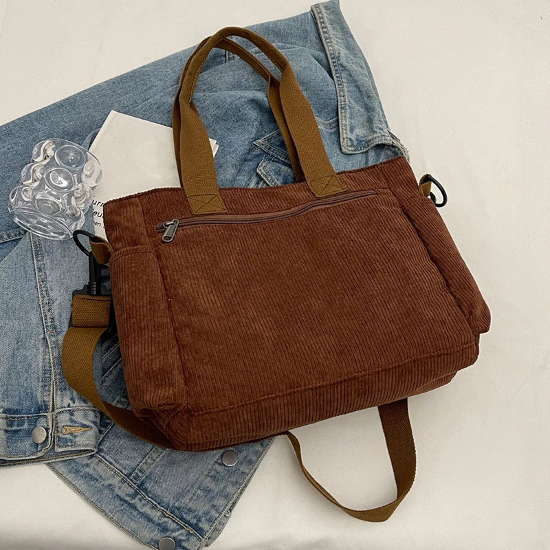 Brown corduroy bag on a white background with denim jacket and glass mug.