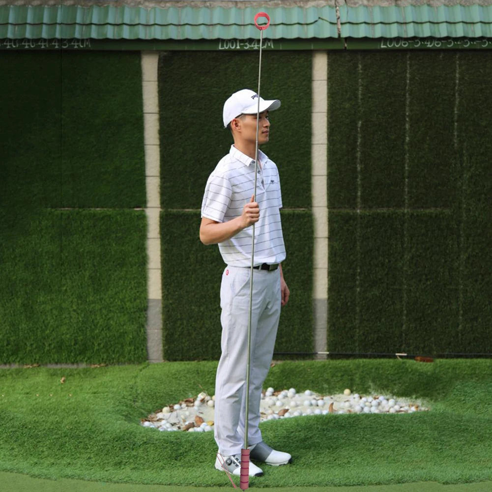 Man in a golf course holding a ball grabber, with a green wall in the background