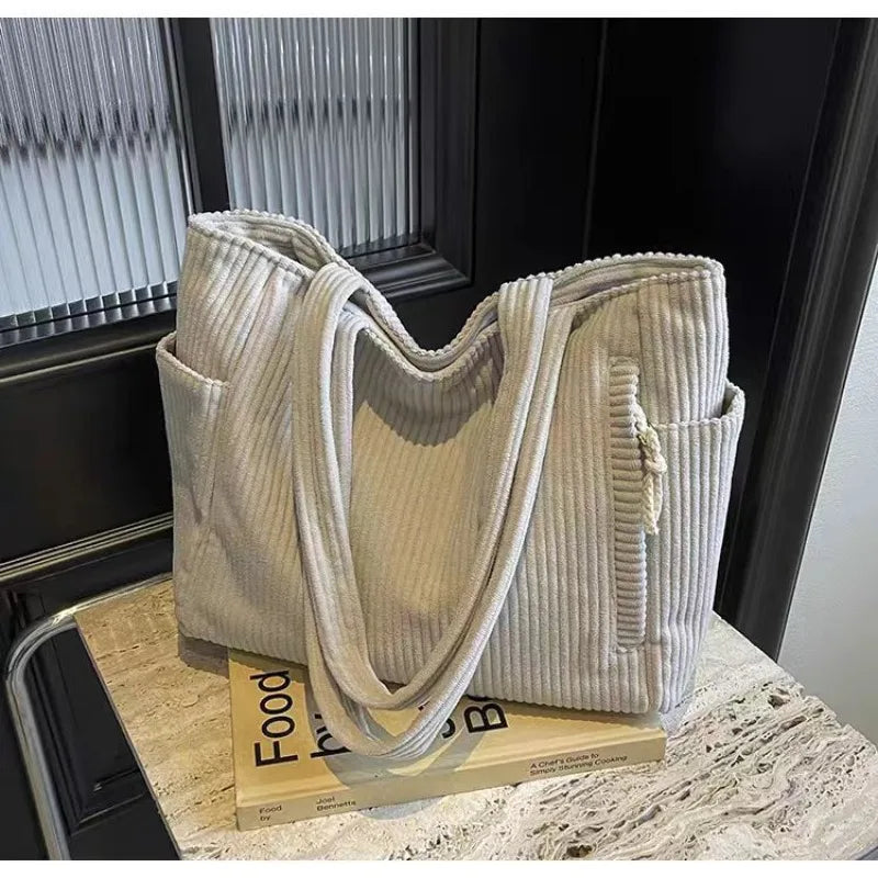 Beige corduroy tote bag on a surface with books underneath