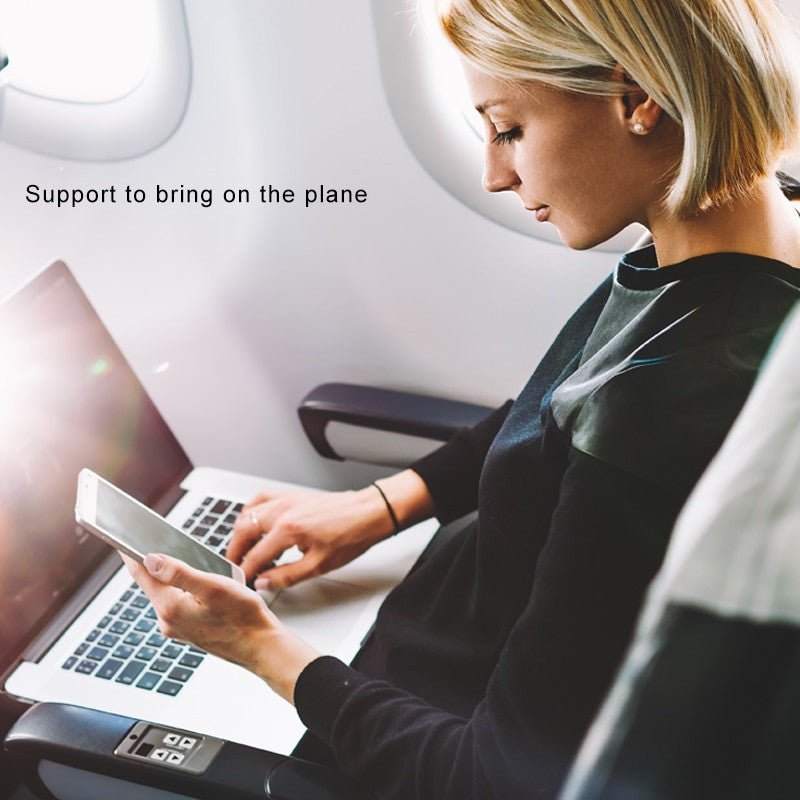 Woman using smartphone while working on laptop aboard an airplane, illustrating the portability of OISLE Universal Type-C Battery External Power Bank.