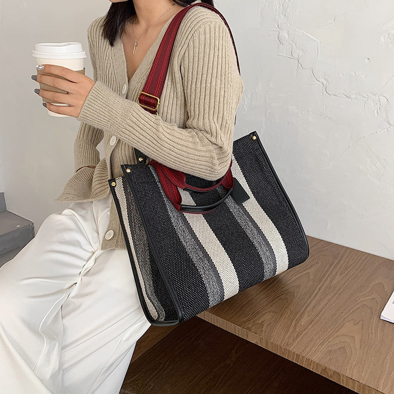 A model sitting on table carrying Women’s Canvas Handbags - Shoulder Bags, Crossbody Bags, and Tote Messenger Bag.